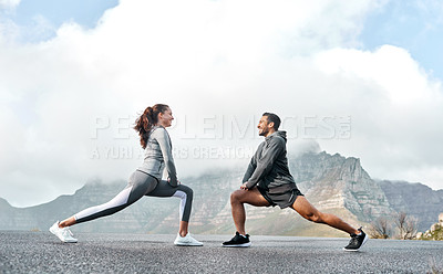 Buy stock photo Shot of a sporty young man and woman stretching their legs while exercising outdoors