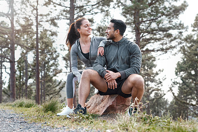 Buy stock photo Shot of a sporty young man and woman taking a break while exercising outdoors