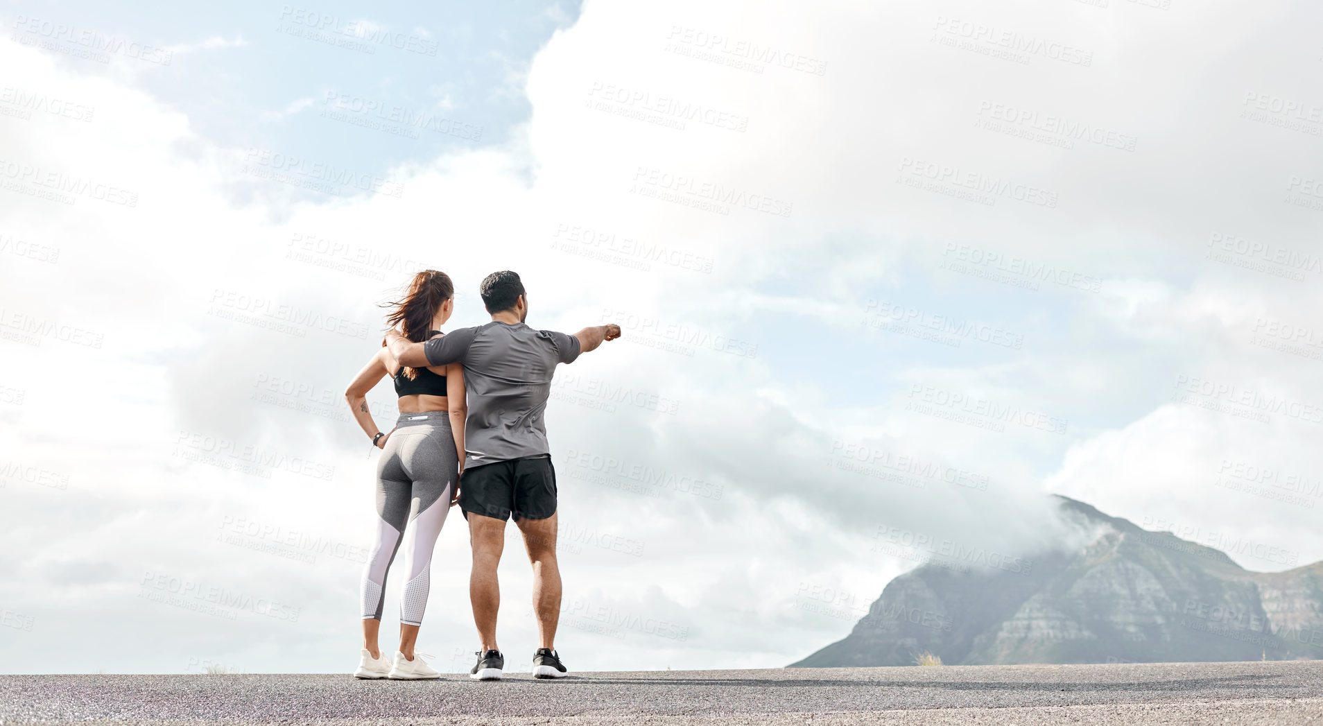 Buy stock photo Rearview shot of a sporty young man and woman looking at the view while exercising outdoors