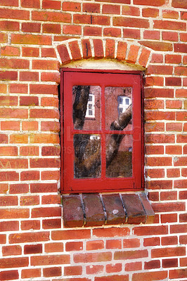 Buy stock photo Dirty window in an old red brick house outside. Background of an architectural built structure on an exterior wall with red wooden windowpanes shut close. Historic building in a traditional town