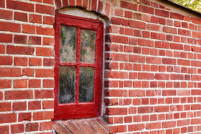 Buy stock photo Old dirty window in a red brick house or home. Ancient casement with red wood frame on a historic building with clumpy paint texture. Exterior details of a windowsill in a traditional town or village