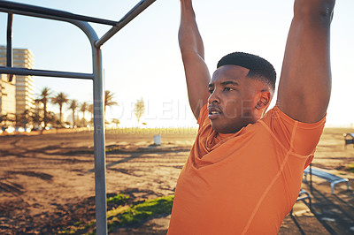 Buy stock photo Shot of a young man working out at the outdoor gym at the park