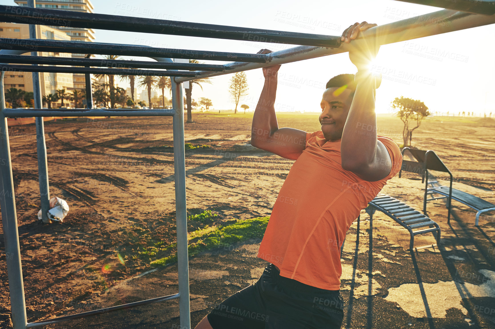 Buy stock photo Shot of a young man working out at the outdoor gym at the park