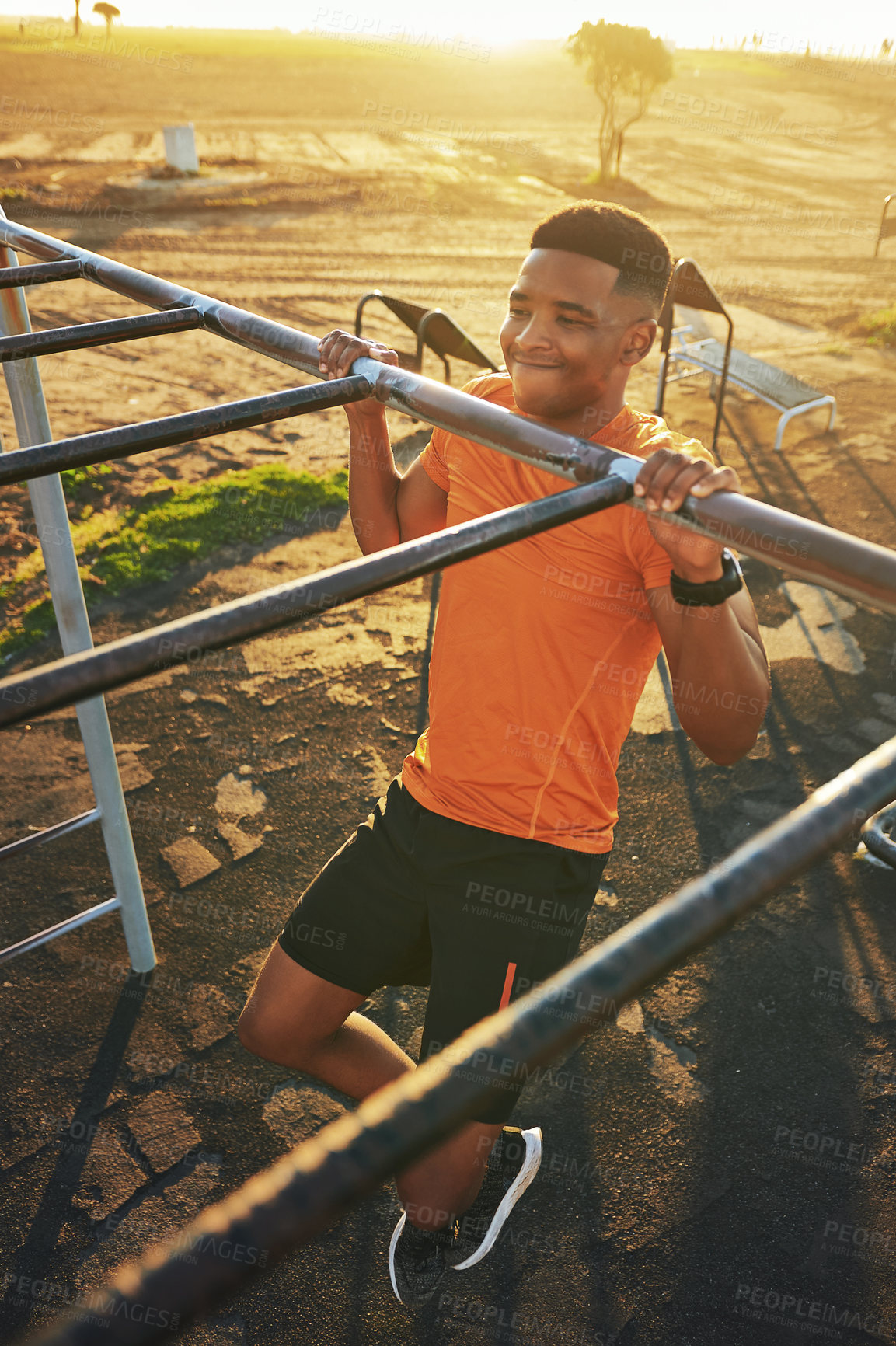 Buy stock photo Shot of a young man working out at the outdoor gym at the park