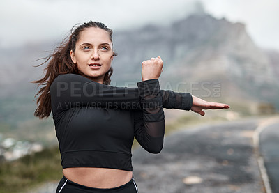 Buy stock photo Cropped shot of an attractive young woman stretching before exercising outdoors alone