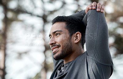 Buy stock photo Cropped shot of a handsome young man stretching before exercising outdoors alone