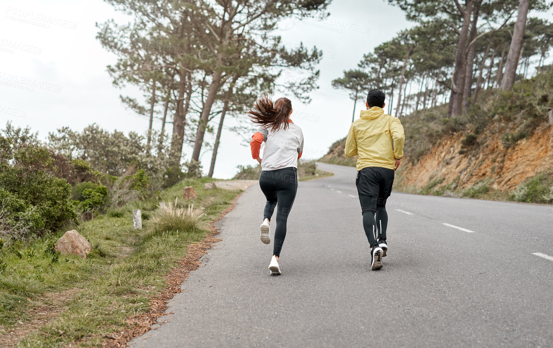 Buy stock photo Full length shot of two unrecognizable athletes bonding together during a run outdoors