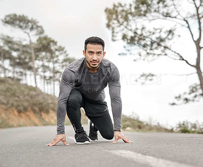 Buy stock photo Full length shot of a handsome young man crouched down in a starters position before exercising outside