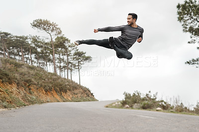 Buy stock photo Full length shot of a handsome young man doing a flying kick during his workout outdoors