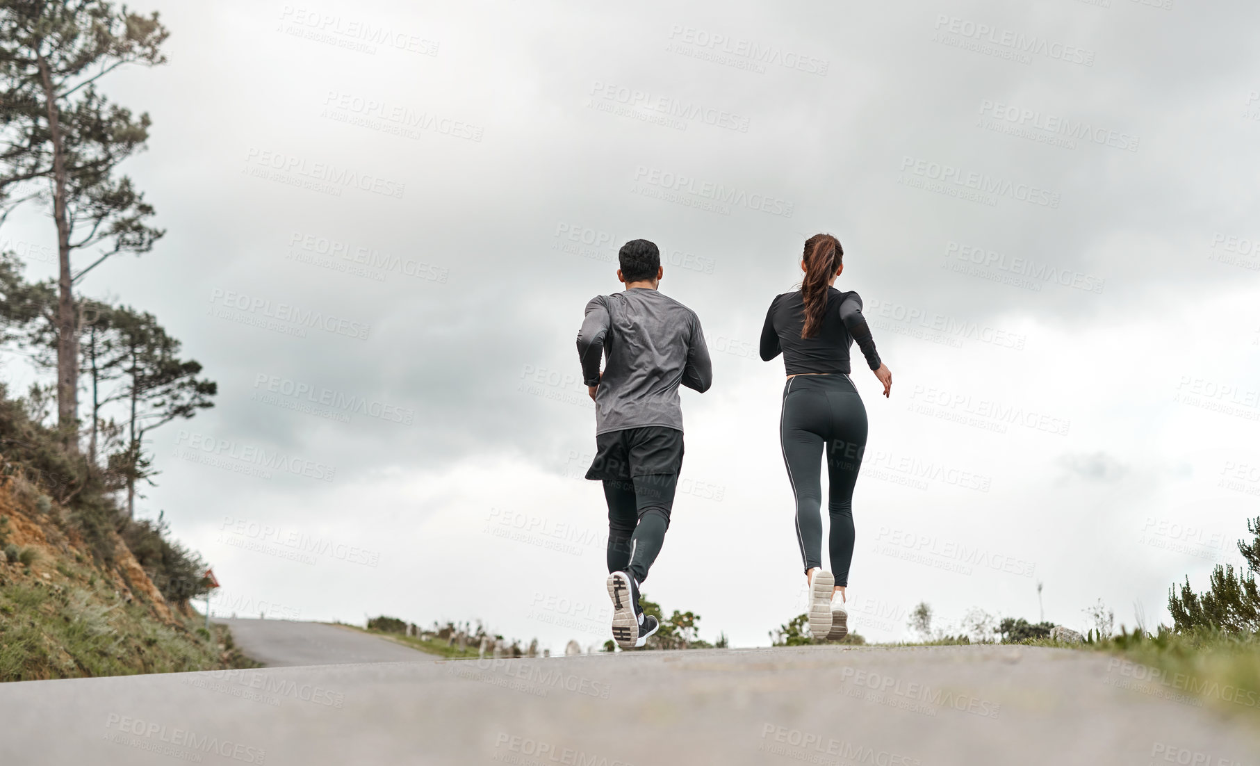 Buy stock photo Full length shot of two unrecognizable athletes bonding together during a run outdoors