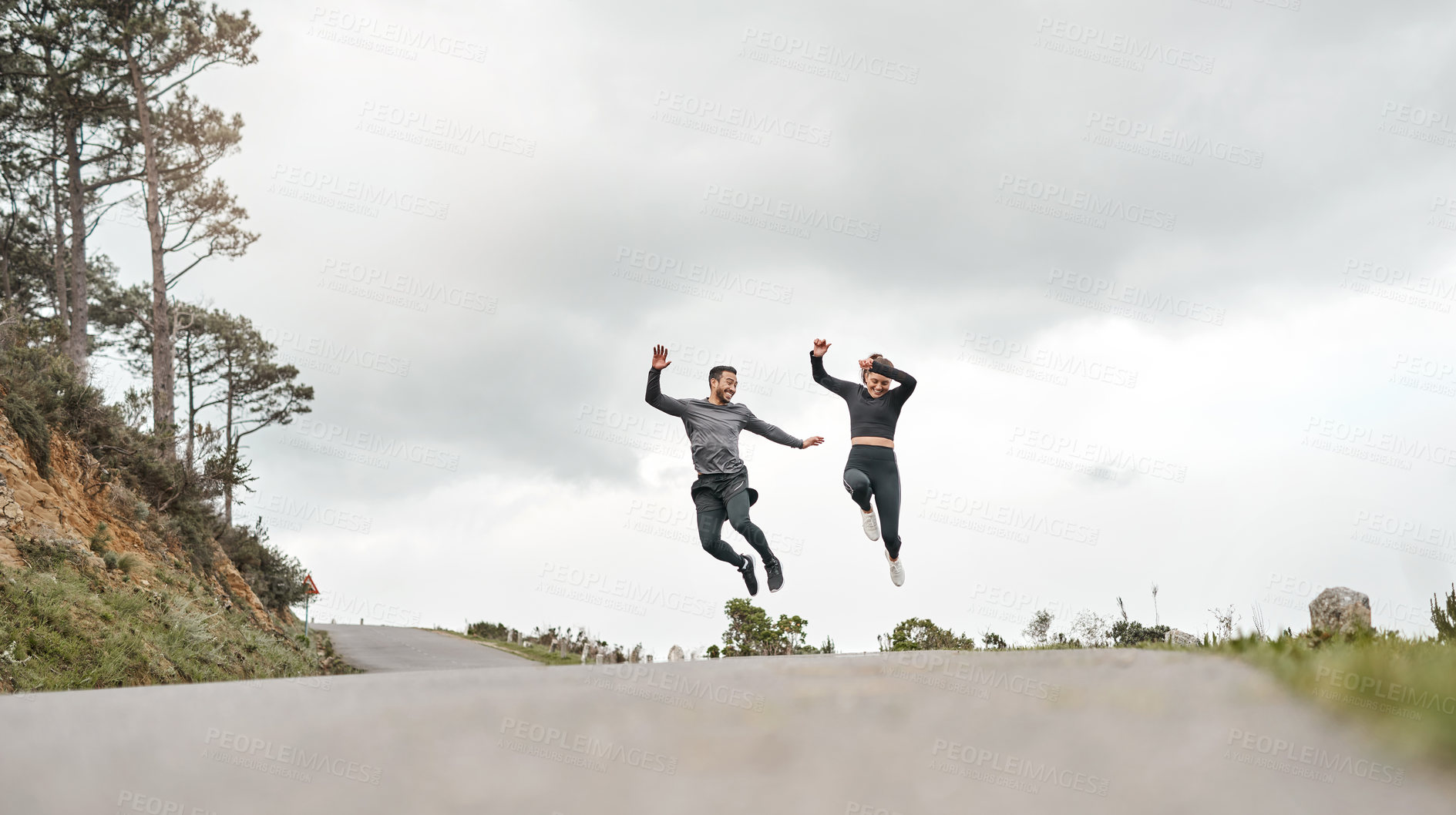 Buy stock photo Full length shot of two young athletes jumping for joy after their morning run outdoors
