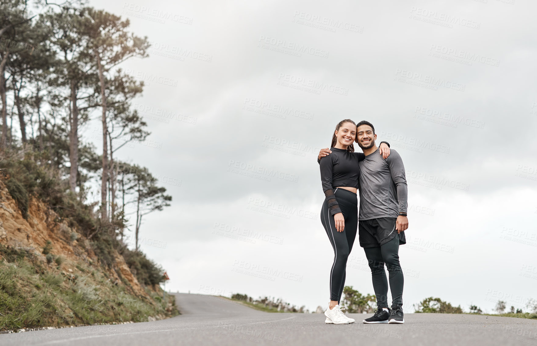 Buy stock photo Full length portrait of two young athletes standing with their arms around each other after their morning run outdoors