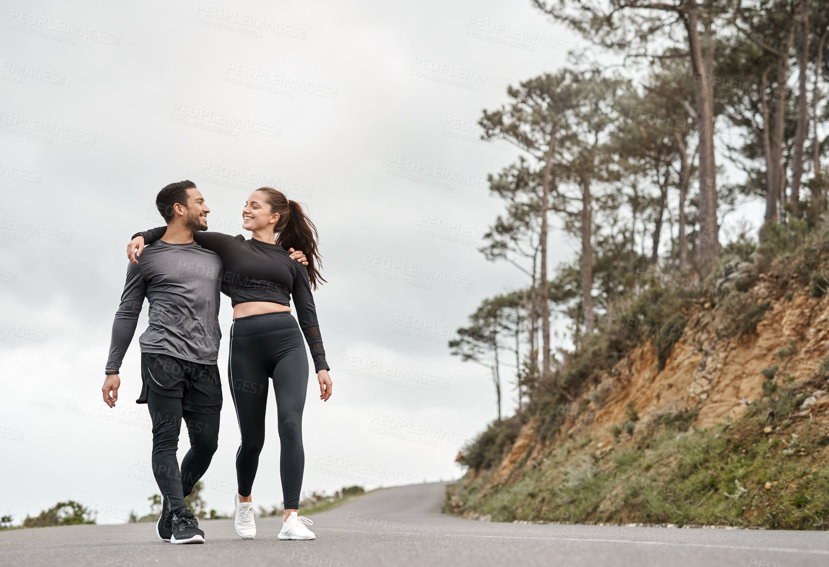 Buy stock photo Full length shot of two young athletes walking with their arms around each other after a run outdoors