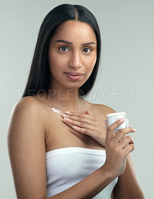 Buy stock photo Shot of a beautiful young woman holding a pot of moisturiser