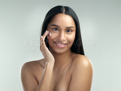 Buy stock photo Shot of a beautiful young woman applying moisturiser to her skin