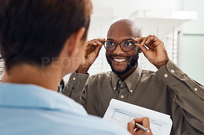 Buy stock photo Shot of a an optometrist helping a young man choose a new pair of glasses