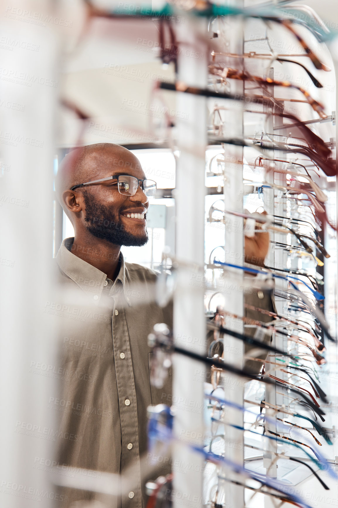 Buy stock photo Shot of a young man buying a new pair of glasses at an optometrist store