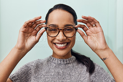 Buy stock photo Shot of a young woman buying a new pair of glasses at an optometrist store