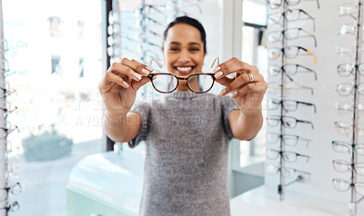 Buy stock photo Female holding pair of trendy new glasses, stylish spectacles and prescription lenses at an optometrist. Portrait of a customer choosing, buying and shopping for frames for better vision and eyesight
