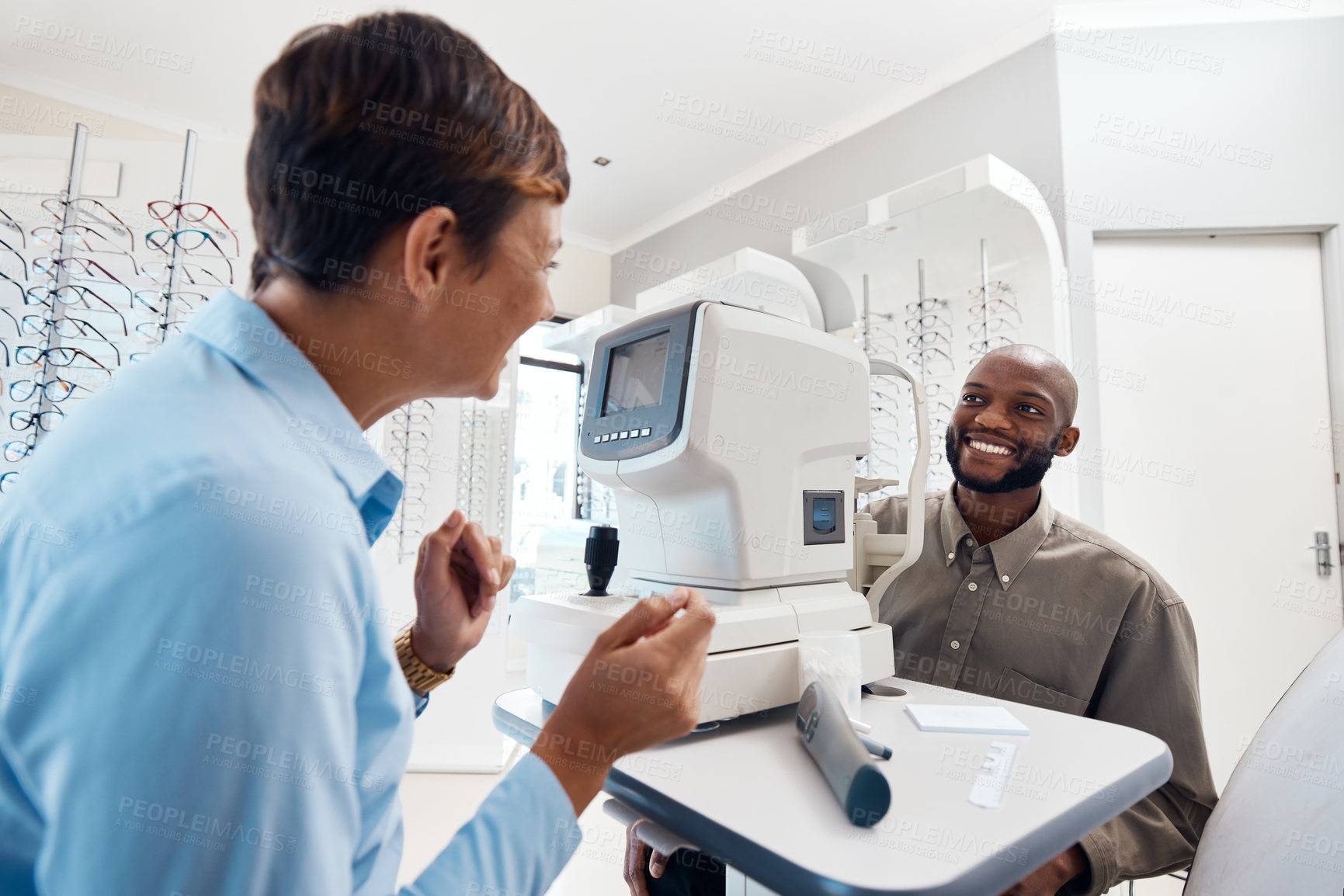 Buy stock photo Shot of an optometrist examining her patient’s eyes with an autorefractor