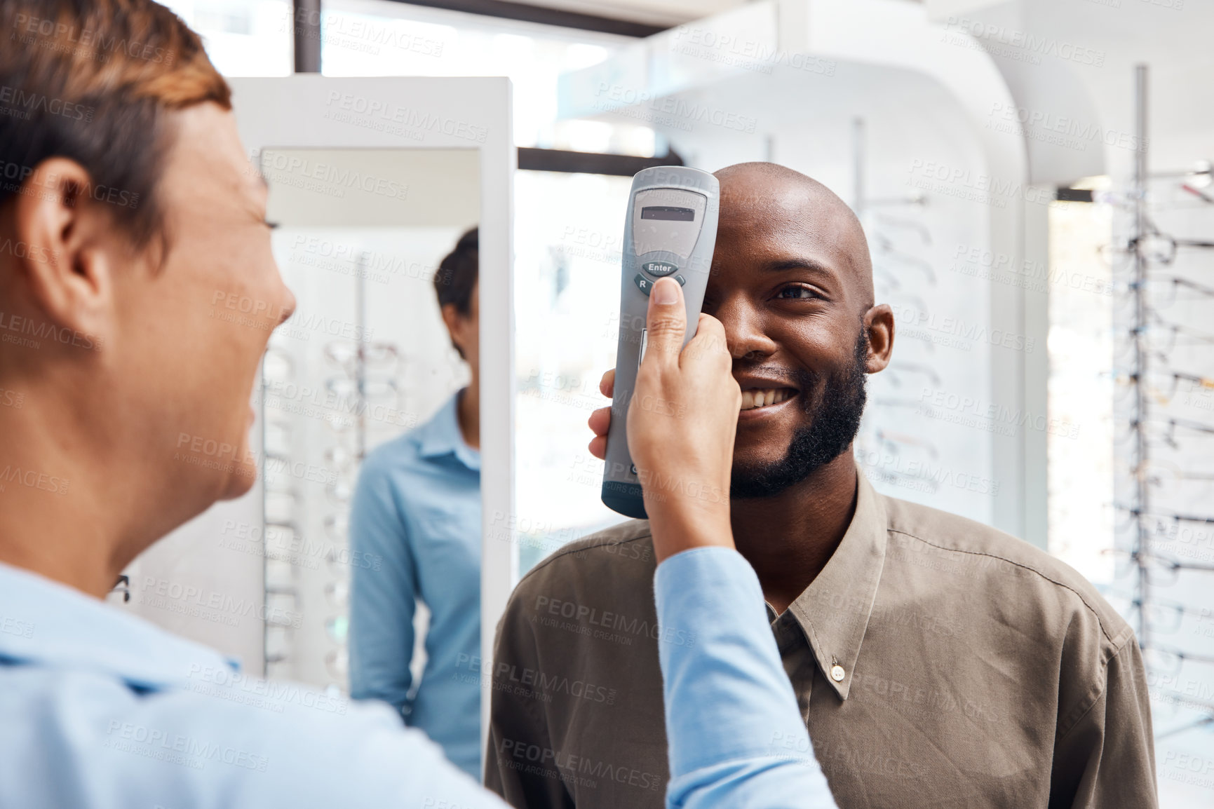 Buy stock photo Eye exam, eyewear and an optometrist checking happy young male eyes with optic medical equipment. African man getting his eyesight checked by a tonometer. Smiling guy getting new spectacles.