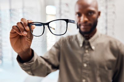 Buy stock photo Shot of a young woman buying a new pair of glasses at an optometrist store