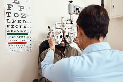 Buy stock photo Shot of an optometrist examining her patient’s eyes with an optical refractor