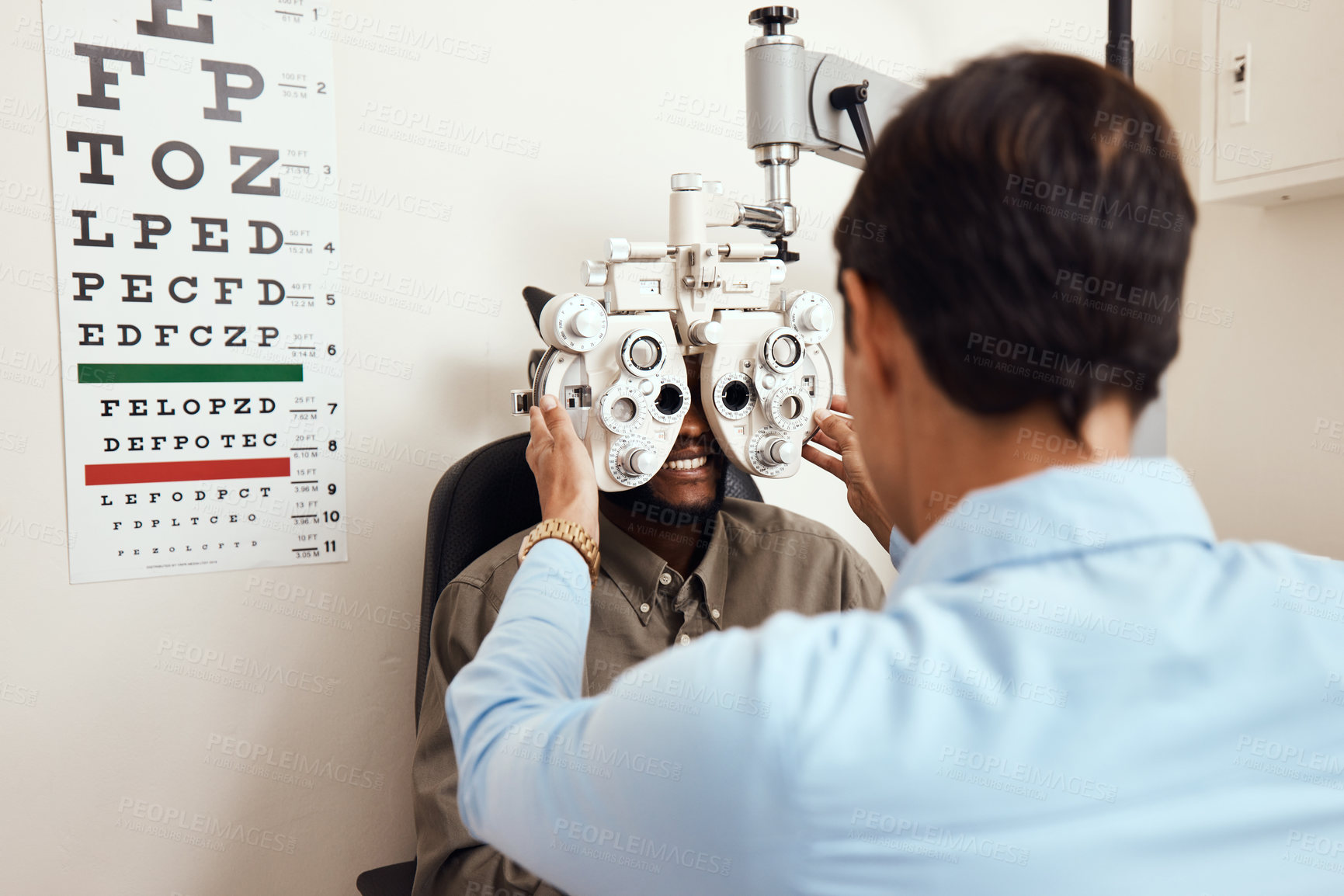 Buy stock photo Shot of an optometrist examining her patient’s eyes with an optical refractor
