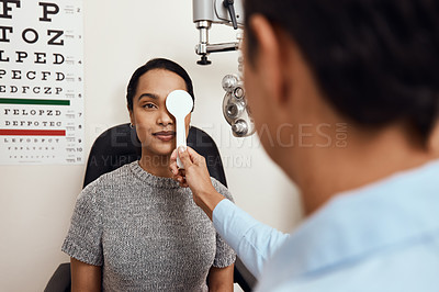 Buy stock photo Eye exam, vision testing at an optometrist with young woman and doctor. Opthamologist using an occluder to test eyesight before being fitted with glasses. Relaxed lady smiling, satisfied with service