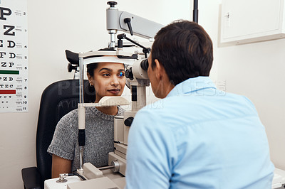 Buy stock photo Shot of a young woman getting her eye’s examined with a slit lamp by an optometrist