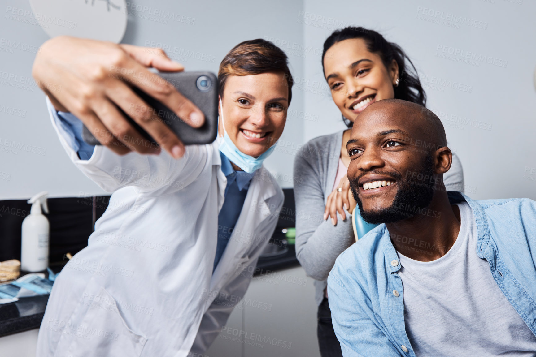 Buy stock photo Shot of a young woman taking selfies with her patient after his dental procedure