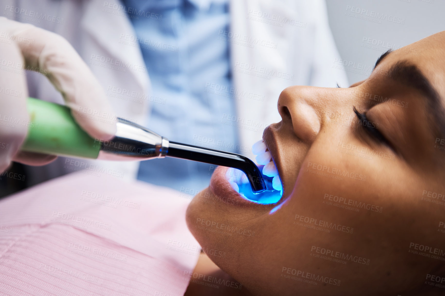 Buy stock photo Shot of a dentist using a curing light on a patient during orthodontic treatment