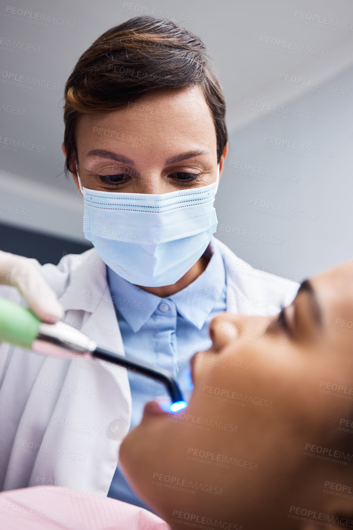 Buy stock photo Shot of a dentist using a curing light on a patient during orthodontic treatment