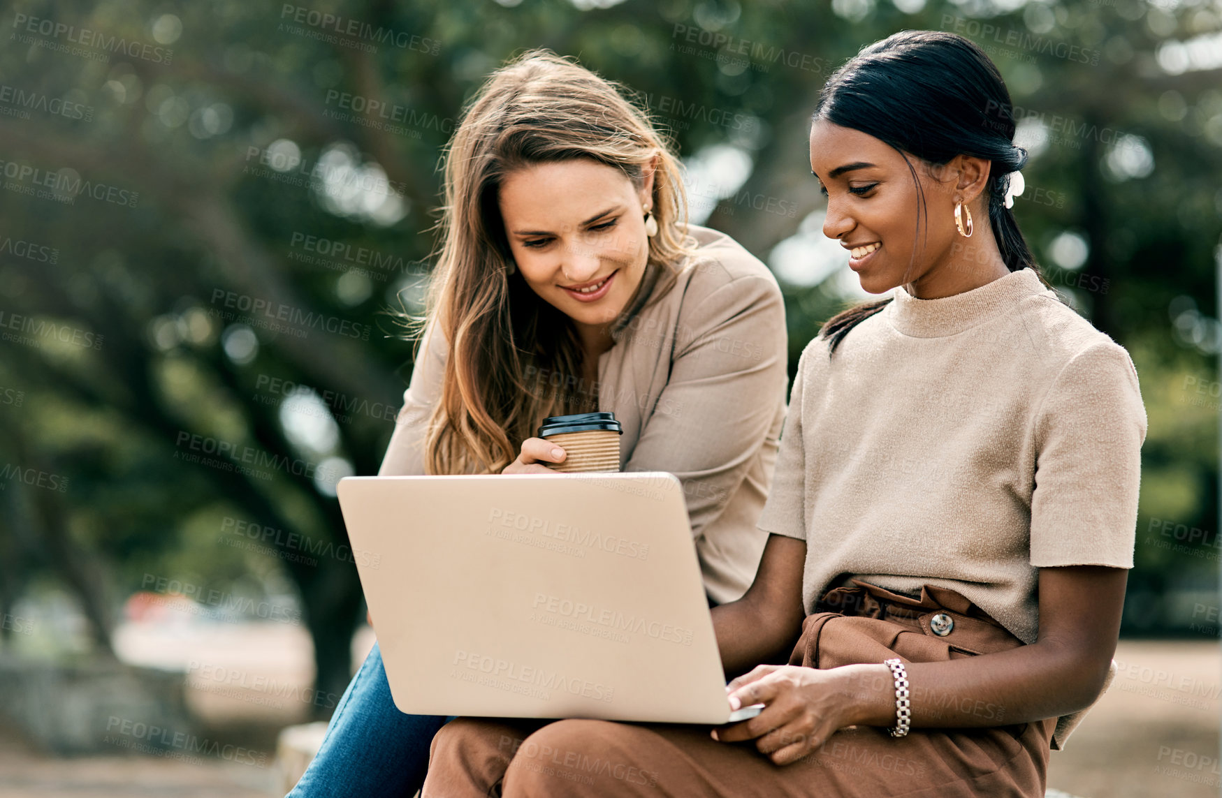 Buy stock photo Shot of two attractive young female students using a laptop while sitting outside on campus