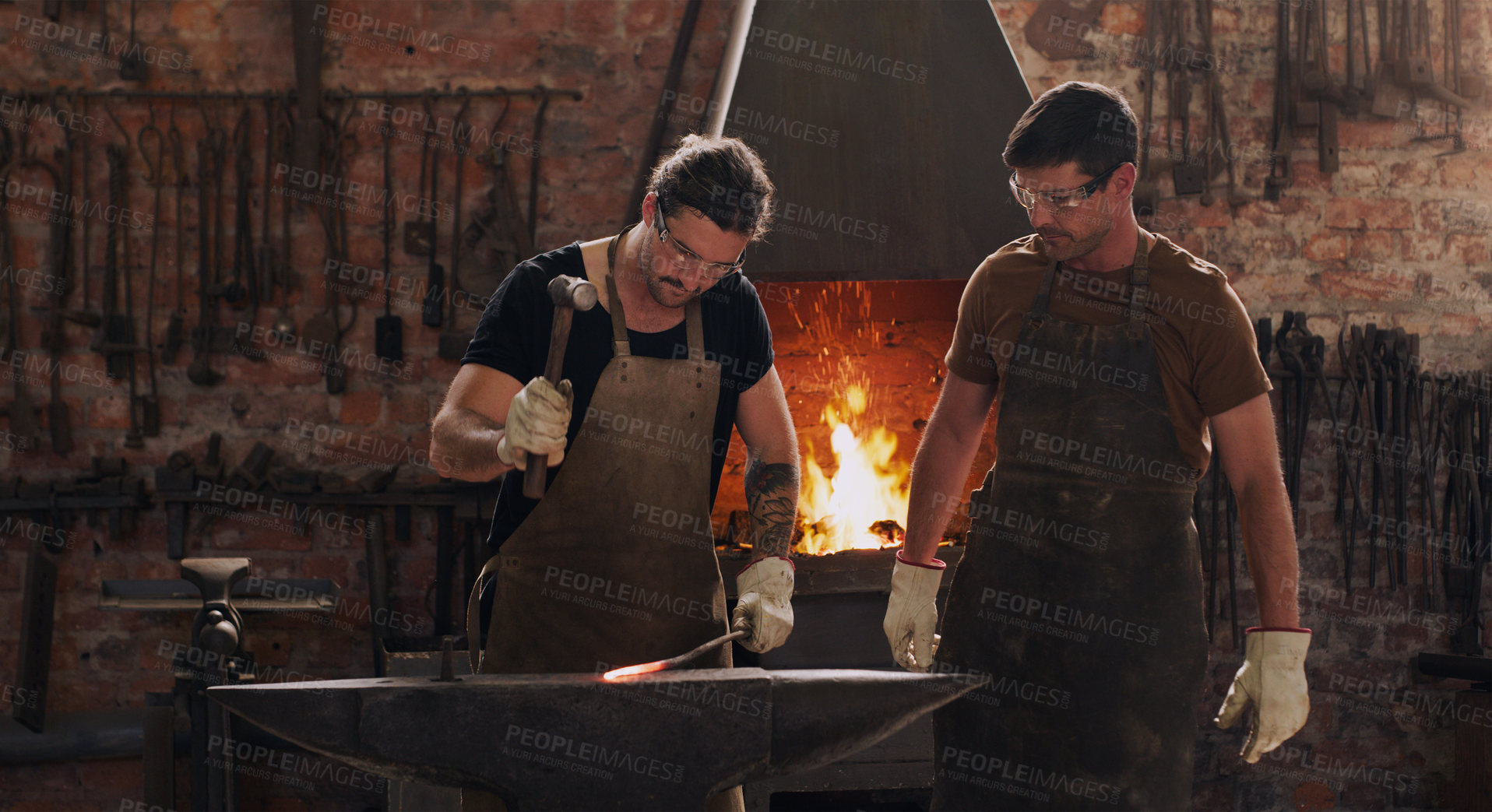 Buy stock photo Hammer, anvil and fire with men working in a forge for metal work manufacturing or production. Industry, welding and trade with blacksmith professionals in a workshop, plant or industrial foundry