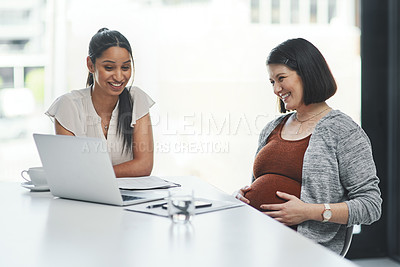 Buy stock photo Shot of a pregnant young businesswoman using a laptop during a meeting with her colleague in a modern office