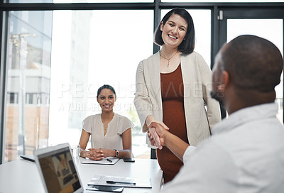 Buy stock photo Shot of a pregnant young businesswoman shaking hands with a colleague during a meeting in a modern office