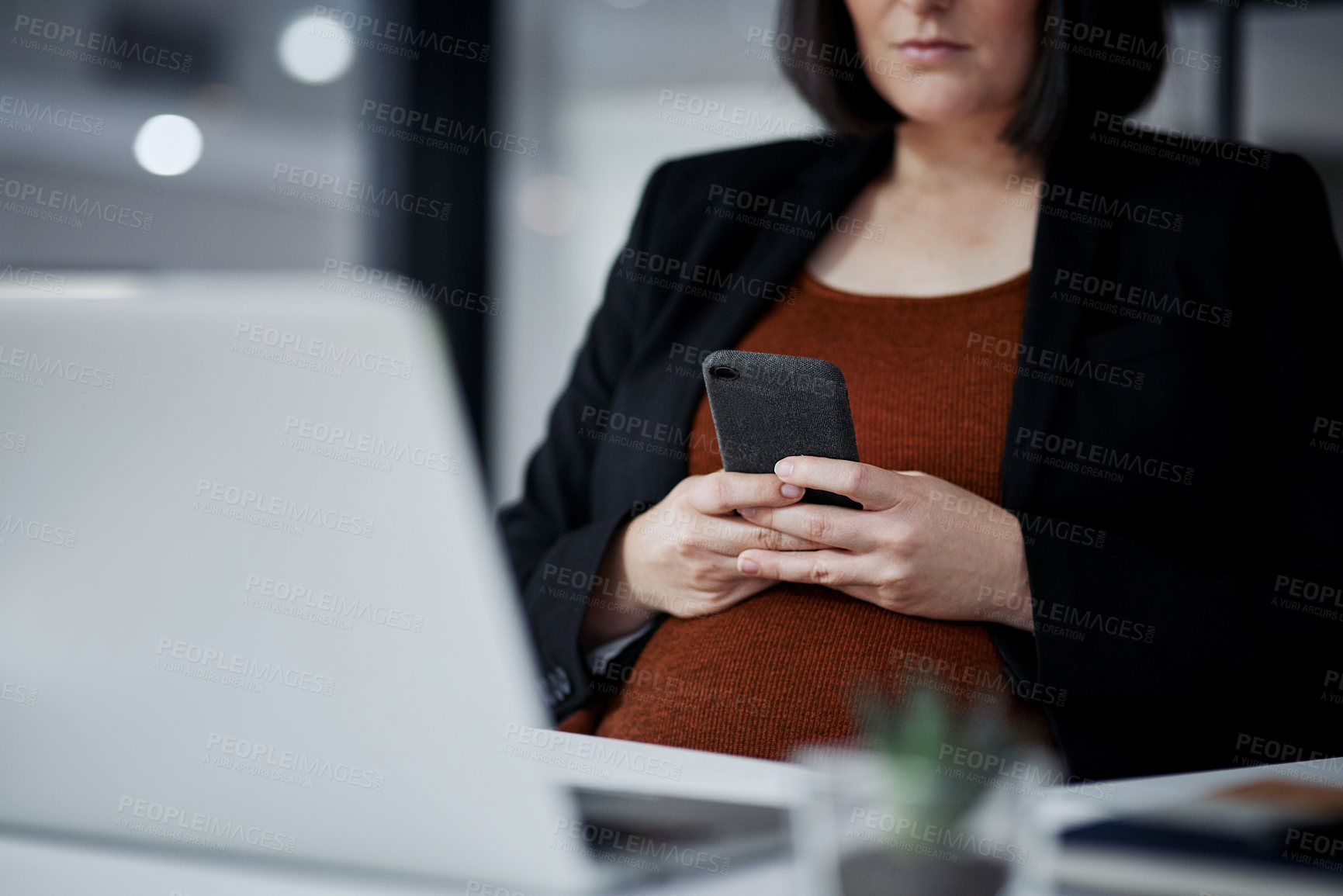 Buy stock photo Cropped shot of an unrecognizable pregnant businesswoman sitting alone and using her cellphone in the office