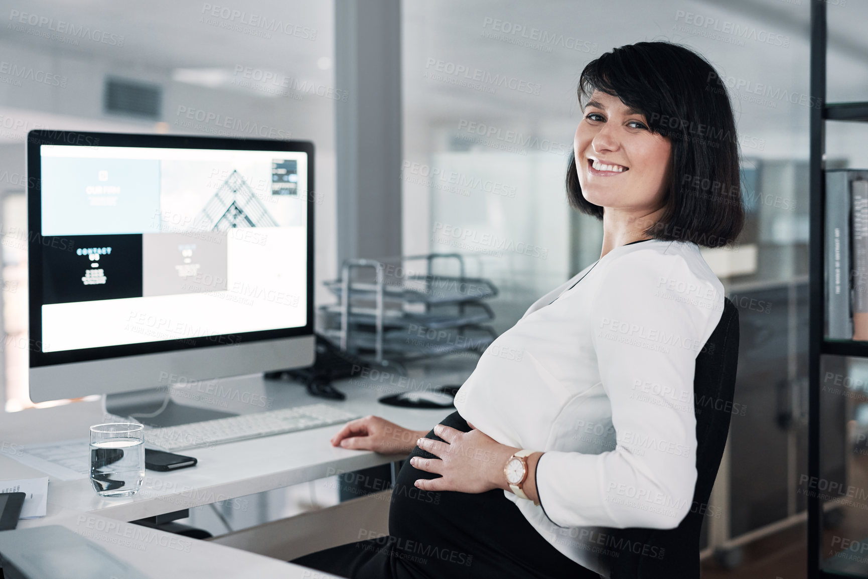 Buy stock photo Cropped shot of an attractive pregnant businesswoman sitting in her office and using her computer while holding her tummy