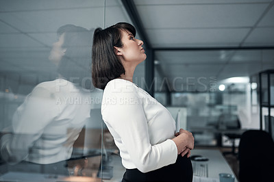 Buy stock photo Cropped shot of an attractive pregnant businesswoman standing alone in the office and feeling overwhelmed