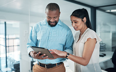 Buy stock photo Cropped shot of two businesspeople standing together in the office and using a tablet