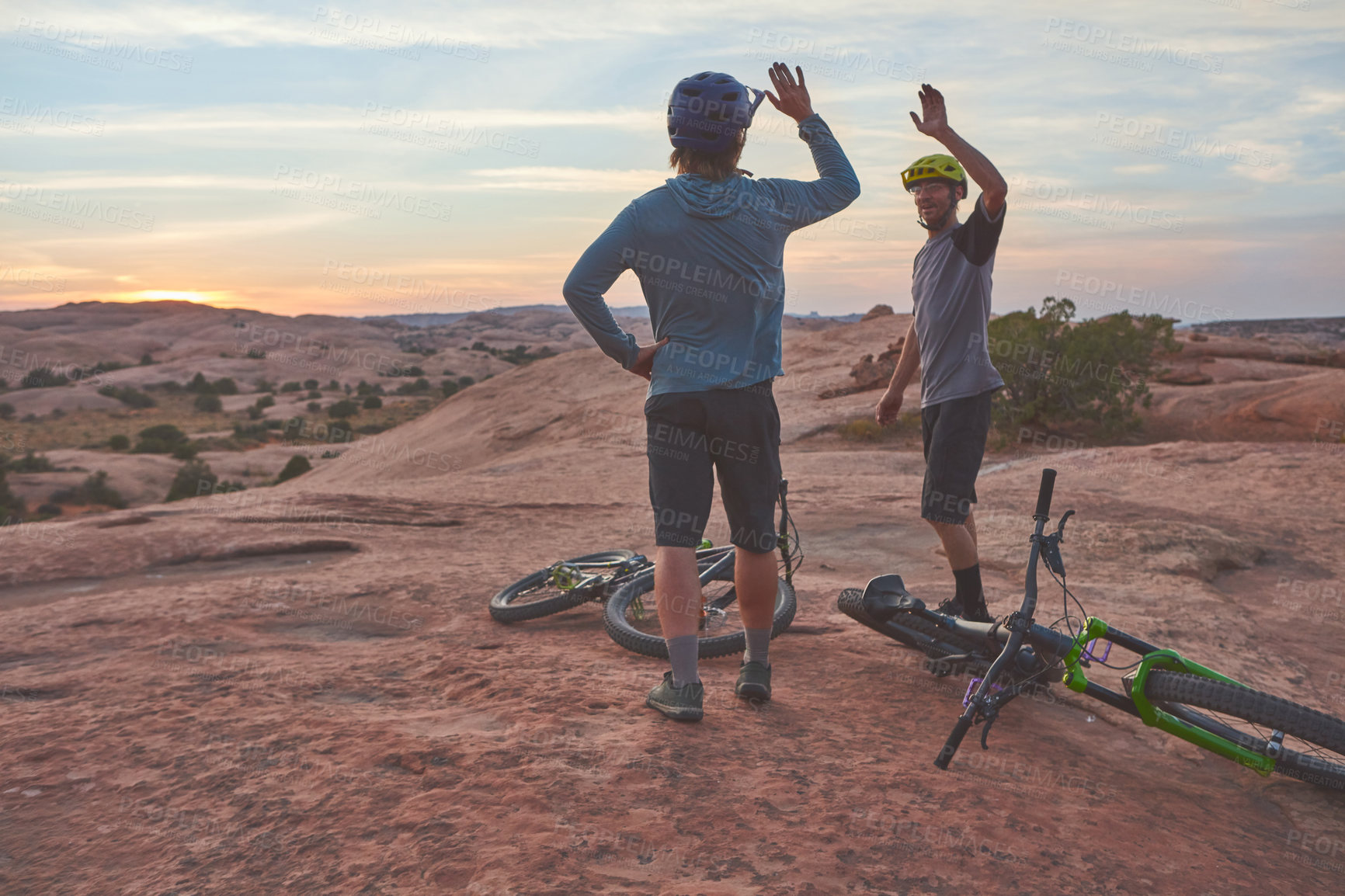 Buy stock photo Shot of two men giving each other a high five while out mountain biking