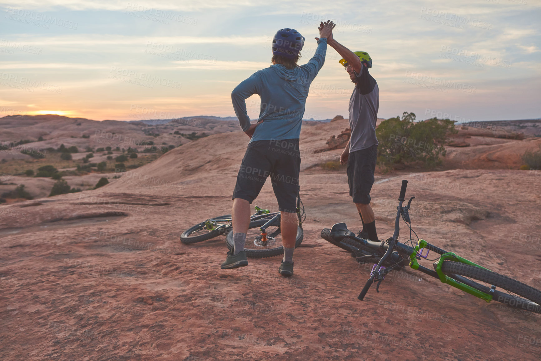 Buy stock photo Shot of two men giving each other a high five while out mountain biking