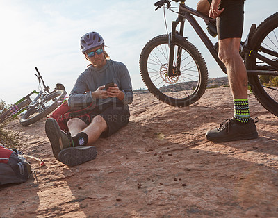 Buy stock photo Cropped shot of two athletic men taking a break while mountain biking through the wilderness