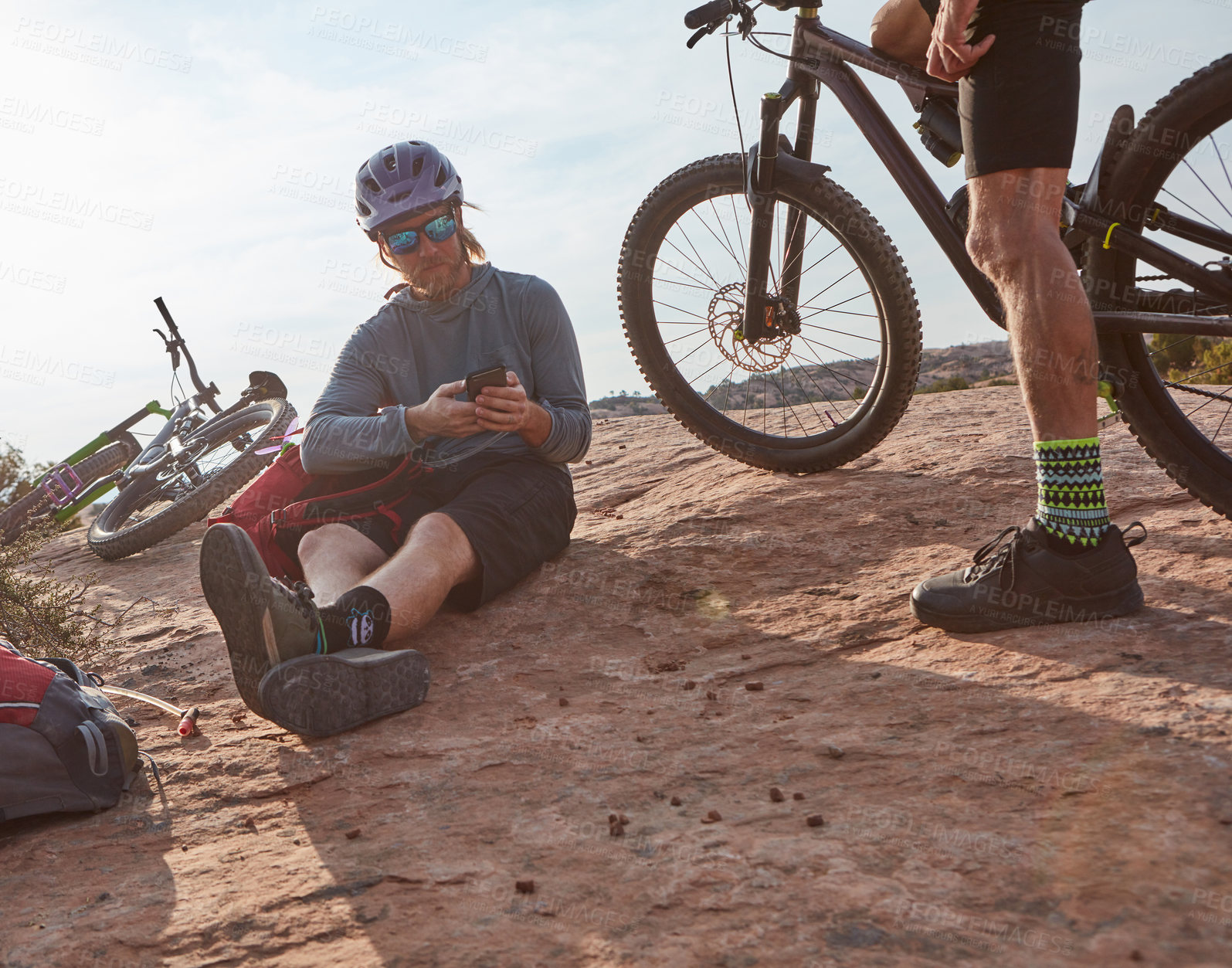 Buy stock photo Cropped shot of two athletic men taking a break while mountain biking through the wilderness