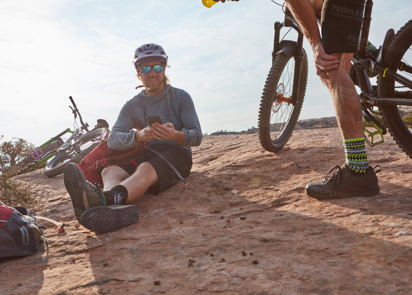 Buy stock photo Cropped shot of two athletic men taking a break while mountain biking through the wilderness