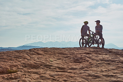 Buy stock photo Full length shot of two athletic men taking a break to admire the view while mountain biking through the wilderness