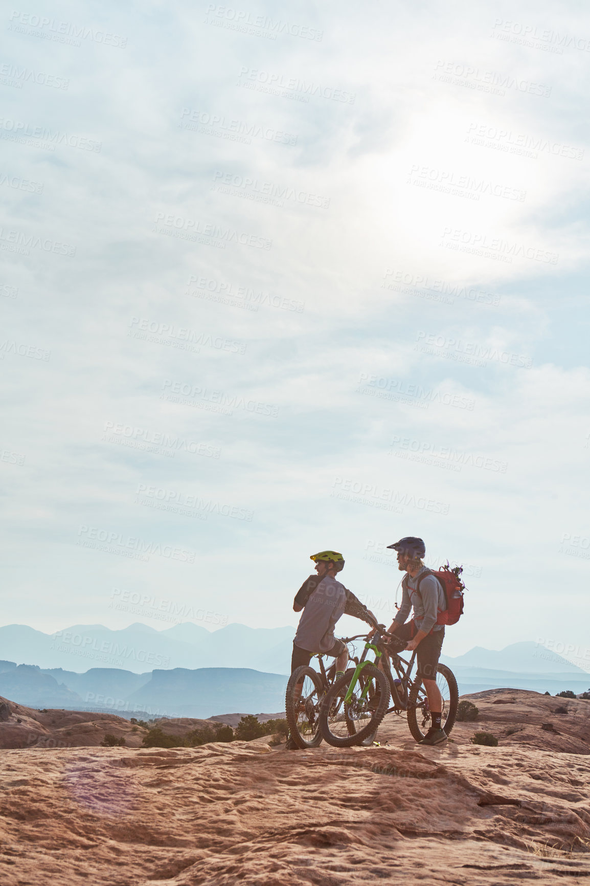 Buy stock photo Full length shot of two athletic men taking a break to admire the view while mountain biking through the wilderness