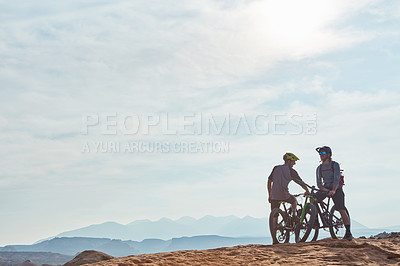 Buy stock photo Full length shot of two athletic men taking a break to admire the view while mountain biking through the wilderness