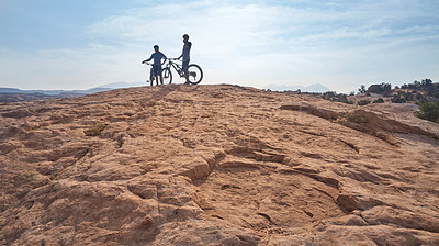 Buy stock photo Full length shot of two athletic men taking a break to admire the view while mountain biking through the wilderness